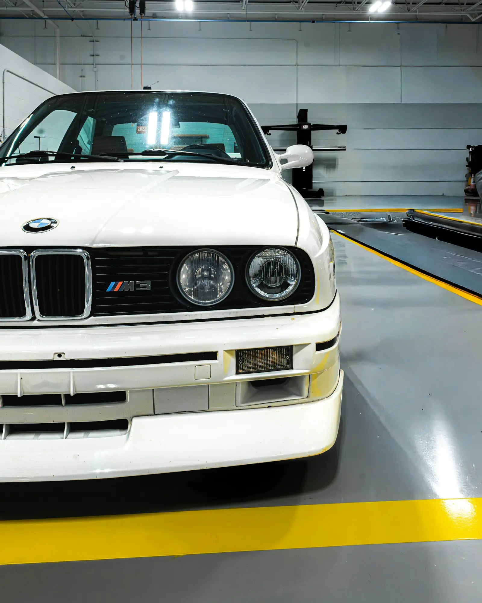 White BMW M3 parked in a repair shop bay