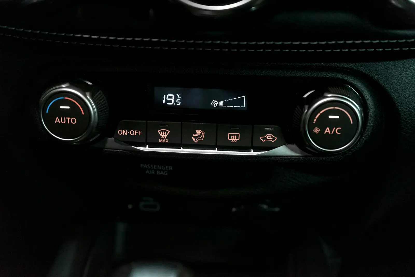 Car climate control panel showing the A/C button and temperature